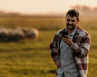 thumbnail of farmer using cellphone infront of stock