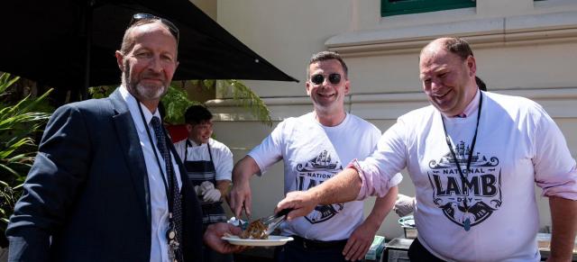 three people eating lamb outside parliament