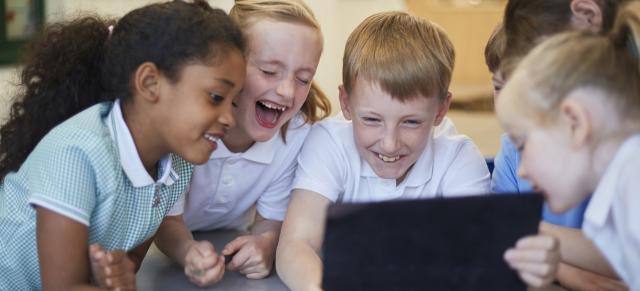 image of boys and girls laughing around laptop