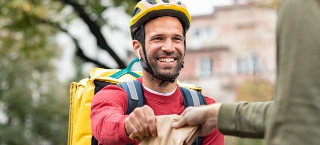 image of man on bike receiving bag of goods