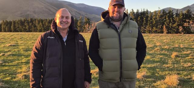 image of two male farmers standing infront of paddock