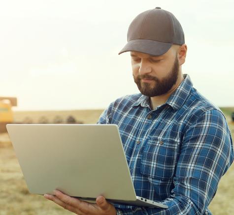 image of farmer with laptop on farm