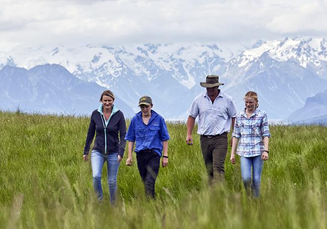 image of farming family working side by side infront of snowy mountians