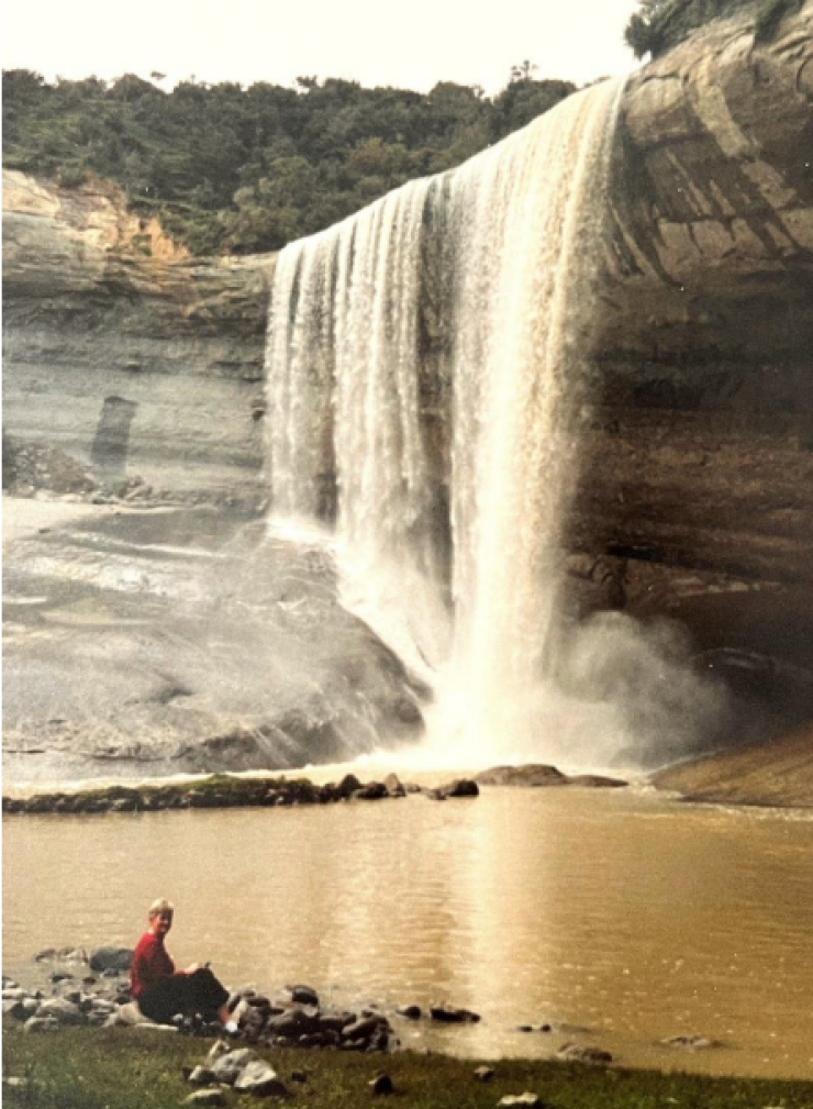 image of person sitting under waterfall in foreground