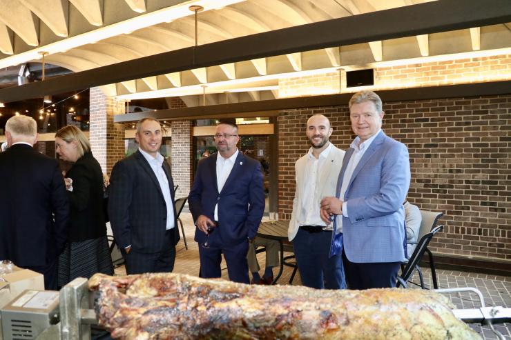 Image of delegates standing behind roasted lamb