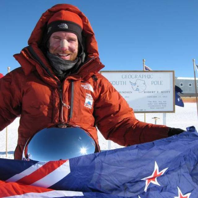 image of Jamie Fitzgerald holding NZ flag in Antarctica