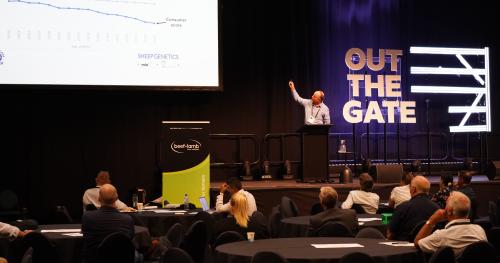 image of speaker pointing at screen at conference