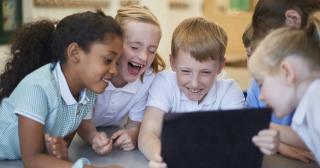 image of boys and girls laughing around laptop