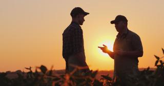 image of younger male talking to older farmer in the sunset