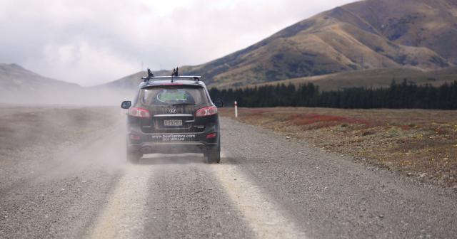 image of car driving on dusty road