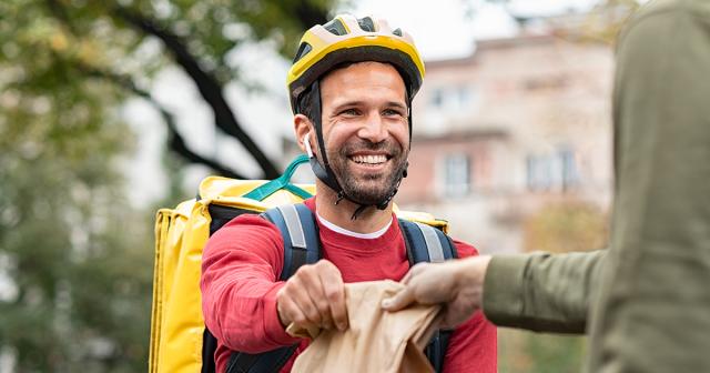 image of man on bike receiving bag of goods