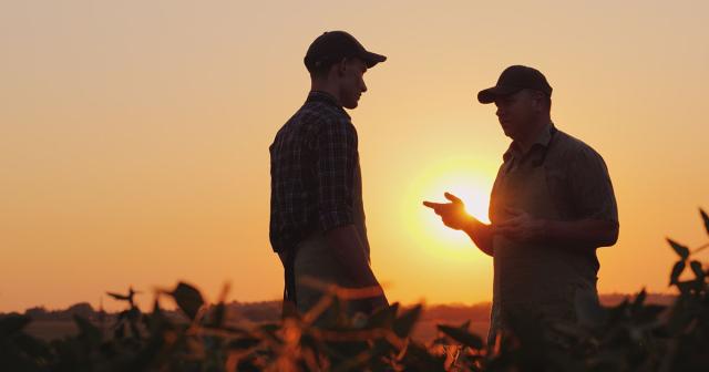 image of younger male talking to older farmer in the sunset