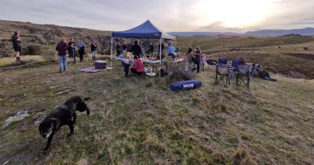 image of catchment group under blue tent. Dog in foreground.