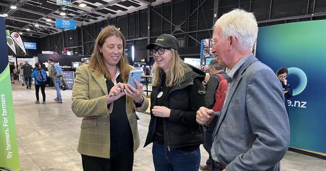 image of three B+LNZ staff members at National fieldays in Hamilton looking at phone and laughinh