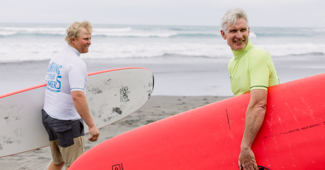 image of two farmers with their surfboards on beach